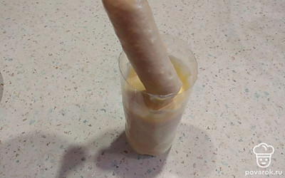 Окуните сосиски в тесто до шпажки и слегка проверните, чтобы оно равномерно распределилось по сосиске.