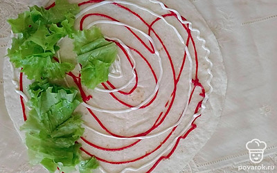 Промойте, нарежьте салат. Распределите по тортилье. 