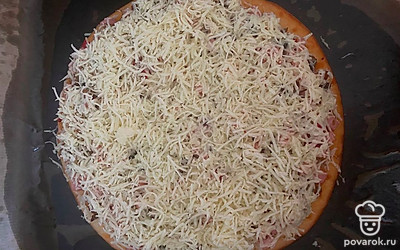 После 20 минут запекания достаем пиццу, посыпаем ее сыром и еще на 5-7 минут отправляем в духовой шкаф, уменьшив температуру до 150 градусов. 