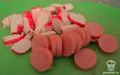 Режем сосиски и крабовые палочки на дольки.