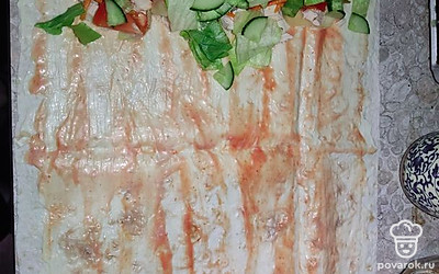 Смазать лаваш сметаной и кетчупом. Выложить сыр, курицу, овощи на один край лаваша.