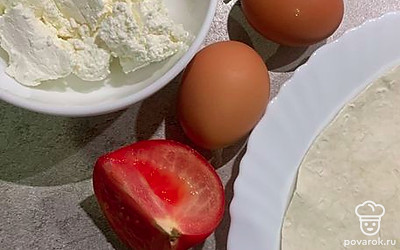 Сварите яйца. Придайте круглую форму лавашу, если у вас он не круглый. Сметану можете заменить йогуртом. Нарежьте зелень, разомните вилочкой творог. 1/4 помидора нарежьте пластинками.