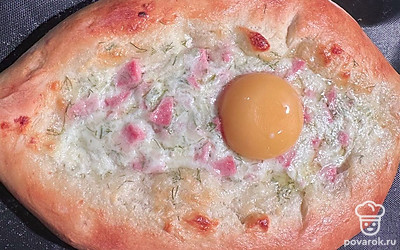 Готовый хачапури выньте из духовки. Выложите сверху сырой желток.