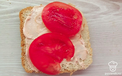 Смажьте один ломтик тостового хлеба соусом. Нарежьте помидор. 