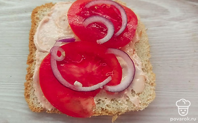 Нарежьте полукольцами лук и выложите поверх помидора.