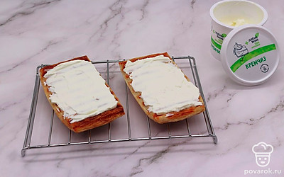 Кусочки грилевого слоеного теста намажьте сливочным сыром. Сверху выложите кусочки лосося. Украсьте бутерброды огурцом, маслинами и укропом.