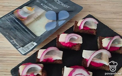 На каждый кусочек выложите сельдь, украсьте ломтиком красного лука и веточкой зелени.