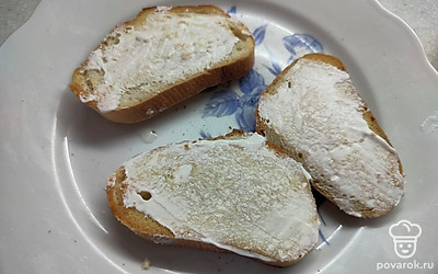 Из ломтиков батона приготовьте гренки. Обжарьте на сухой сковороде или в тостере. Смажьте их тонким слоем сметаны. 