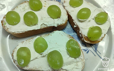 Следующим слоем распределите творожный сыр. Разложите разрезанный пополам виноград. 