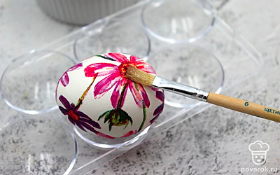 Возьмите первый фрагмент рисунка, приложите его к остывшему яйцу, а сверху кисточкой нанесите в один слой яичный белок. Сделайте декупаж всех яиц. Дайте просохнуть наклеенным рисункам.