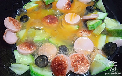 Залейте яйцами кабачок, сосиску и маслины.