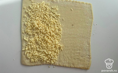 На половину пласта выложите тертый сыр.