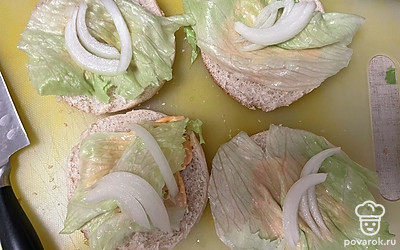 Булочки разрежьте пополам, смажьте соусом. Выложите лист айсберга и немного лука порционно.