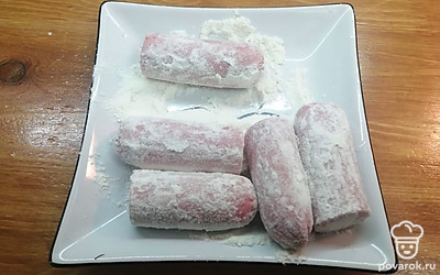 В тарелку насыпьте муку. Обваляйте сосиски. 