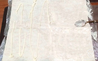 Расстелите на пищевой пленке лаваш. Смажьте тонким слоем майонеза. 