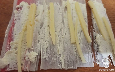 Намажьте крабовые палочки творогом с чесноком. Выложите сыр, как на фото.