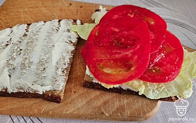 Помидор помойте и нарежьте слайсами. Выложите начинку на одну часть хлеба (листья пекинской капусты, помидоры), посолите по вкусу. 