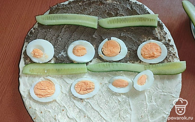 Поверх майонеза выложите половину баночки шпротного паштета, огурцы. Нарежьте яйца. 