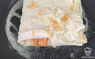 Лаваш окуните в воду и тут же достаньте. На сковороде разогрейте сливочное масло. Выложите лаваш на сковороду с маслом. Вылейте начинку. Заверните лаваш конвертиком и обжарьте с двух сторон под крышкой на среднем огне.