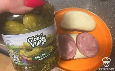 Маринованный огурец нарежьте тонкими ломтиками и выложите сверху.