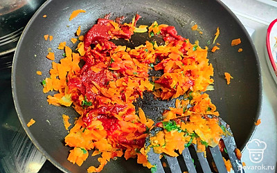 В оставшуюся зажарку выложите томатную пасту, зелень и специи. Добавьте 100 миллилитров кипятка. Немного потушите и снимите с плиты. 