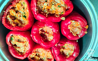 В кастрюлю сложите перцы, очищенные от семян и плодоножек. Заполните их начинкой. Сверху выложите томатную зажарку. Залейте кипятком ниже уровня перцев. Доведите до кипения и готовьте под крышкой 45 минут. 