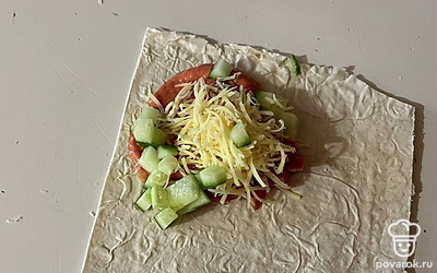 Поверх соуса распределите нарезанные колбасу, огурец и тертый сыр. 