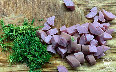 Нарежьте вареные сосиски и зелень.