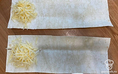 Натрите сыр на крупной терке. Выложите сыр на край каждой полоски лаваша.