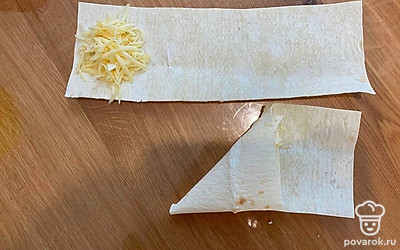 Сверните лаваш с сыром в виде треугольника. Оставшиеся края лаваша отправьте в получившийся кармашек. 