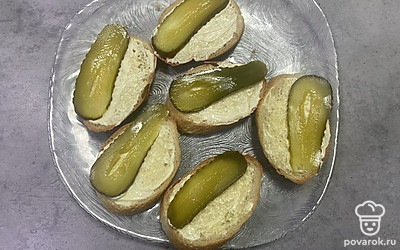 Огурцы нарежьте вдоль, выложите по одному кусочку огурца на каждый кусочек хлеба. 