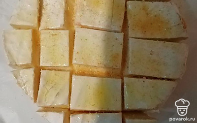 Сыр побрызгайте оливковым маслом из распылителя. Посыпьте сушеным чесноком так, чтобы он попал в надрезы. 