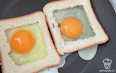 На раскаленную сковороду положите ломтики хлеба без середины и вбейте яйцо. 