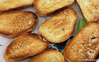 Нарежьте батон или багет на тонкие кусочки и поджарьте хлеб. Сделать это можно в духовке или на сковороде. Я делаю в тостере. Пока хлеб горячий, смажьте его чесноком с двух сторон.