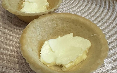 В тарталетки выложите сливочное масло.