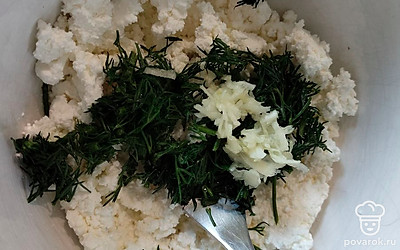 Измельчите вилкой творог. Добавьте к нему мелко нарубленную зелень и чеснок.