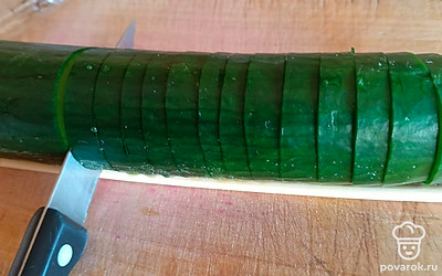 Нашинкуйте средними слайсами весь огурец, упираясь ножом в палочки.