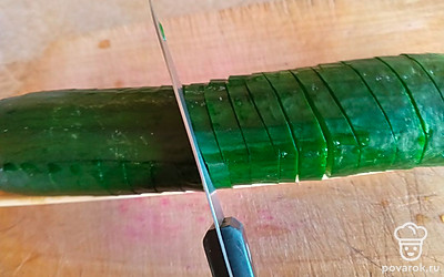 Затем переверните овощ и нарежьте его поперек. Делайте это аккуратно, чтобы огурец полностью не разделился.