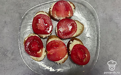Выложите кружки помидора на хлебные тосты. 