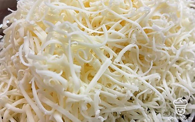 Сыр натереть на мелкой терке, разделить на две части. Одну часть смешать с основной массой.