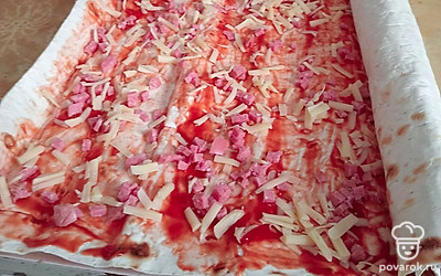 На лаваш тонко намазать кетчуп, посыпать колбасой и сыром, свернуть в рулет.