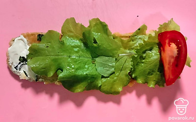 На каждый обжаренный язычок кабачка положите творожный сыр. На одну сторону выложите примерно 1-1,5 чайных ложки творожного сыра и немного на самый край. Это нужно, чтобы рулет не разворачивался. Сверху положите слой салатных листьев и четвертинку помидора, чтобы он выходил за края слайса. С той стороны, где будет лежать помидор, начните сворачивать. Помидор будет загадочно выглядывать из серединки каждого рулетика.