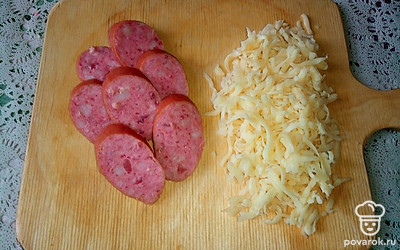 Нашинкуйте копченую колбасу кружочками, а сыр натрите на крупной терке.