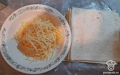 Сыр натереть на терке. Листы лаваша разрезать на небольшие квадраты.