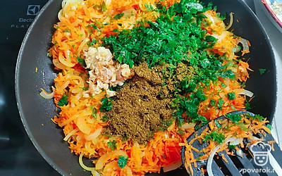 Когда овощи станут мягкими, приправить петрушкой, измельченным чесноком и хмели-сунели. Потушить еще пару минут. 2/3 от всей зажарки отложить. 