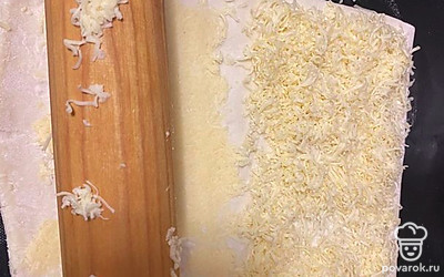 Выложите сыр на пласт теста и с помощью скалки раскатайте, вкатывая сыр в тесто.