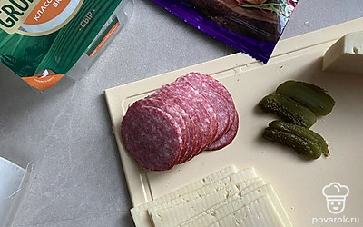 Нарежьте ломтиками колбасу или ветчину, сыр и соленые огурцы.