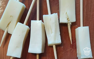 Режем сыр на 6 равных частей. Форму кусочка вы увидите на фото. Одеваем аккуратно сыр на шпажку, проделываем это с каждым кусочком. 