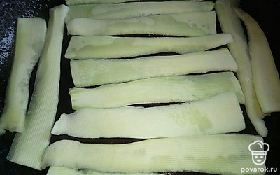 Кабачок очистите и нарежьте тонкими полосками с помощью овощечистки. Обжарьте на растительном масле до румяной корочки полоски кабачка.