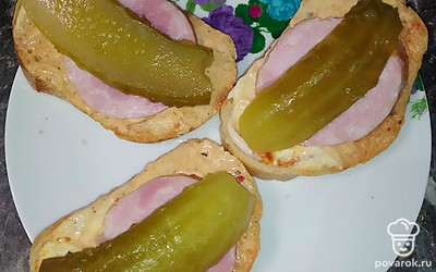 Разрезать на 3 части огурец, выложить поверх колбасы.